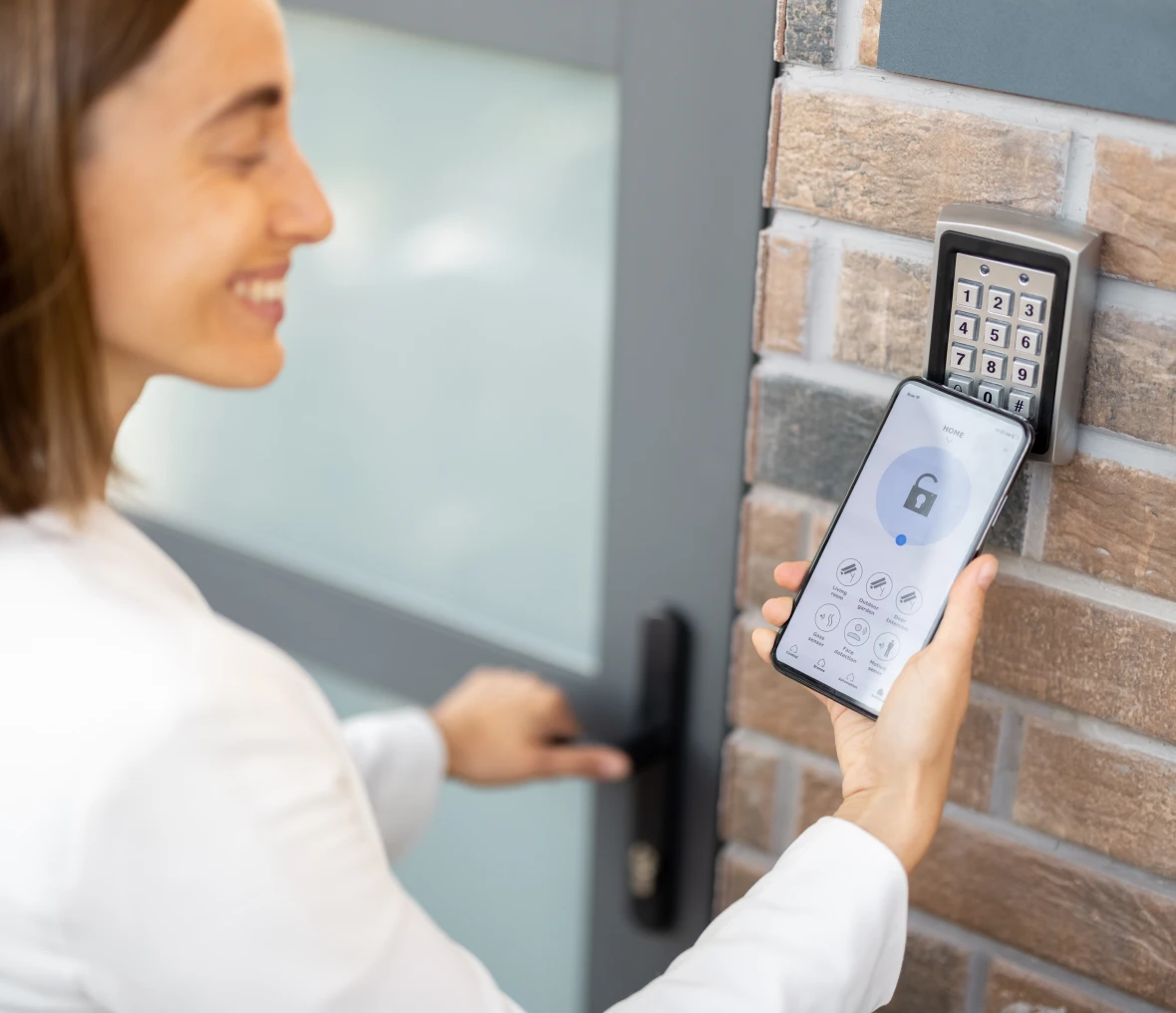 Woman unlocking a door using her mobile home surveillance system.