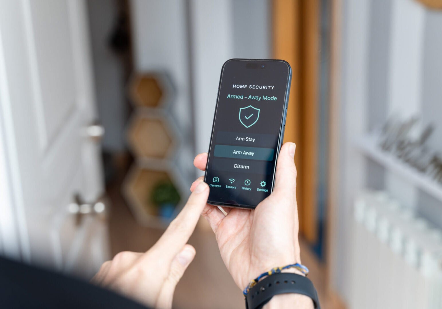 Person using home security app on smartphone.